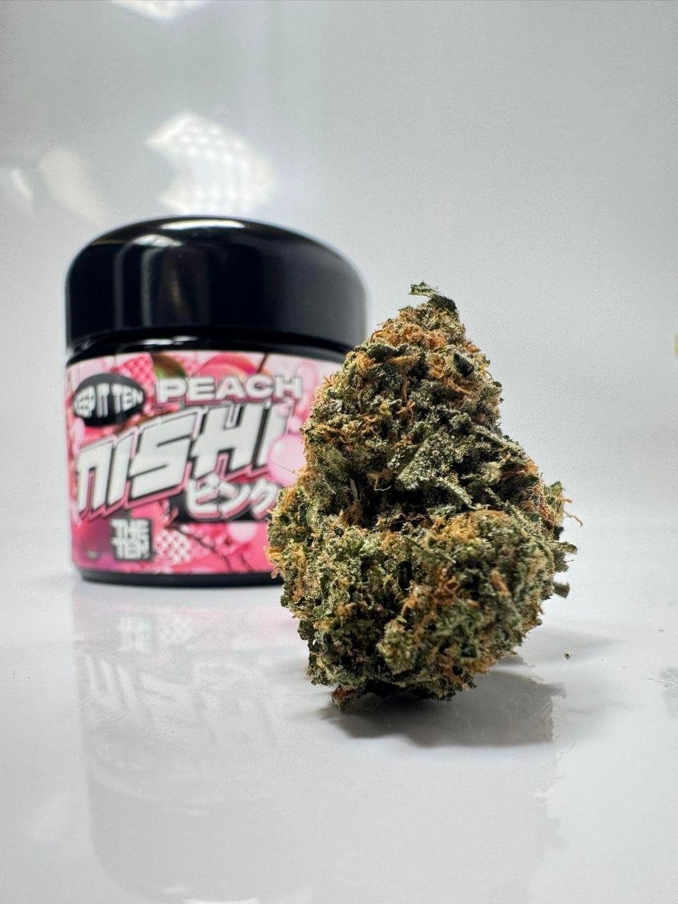 PEACH NISHI By TENCO cannabis bud next to sealed jar – dense frosty nugs with orange pistils